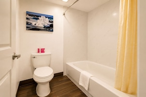 A bathroom with a toilet, a bathtub, and a shower curtain.