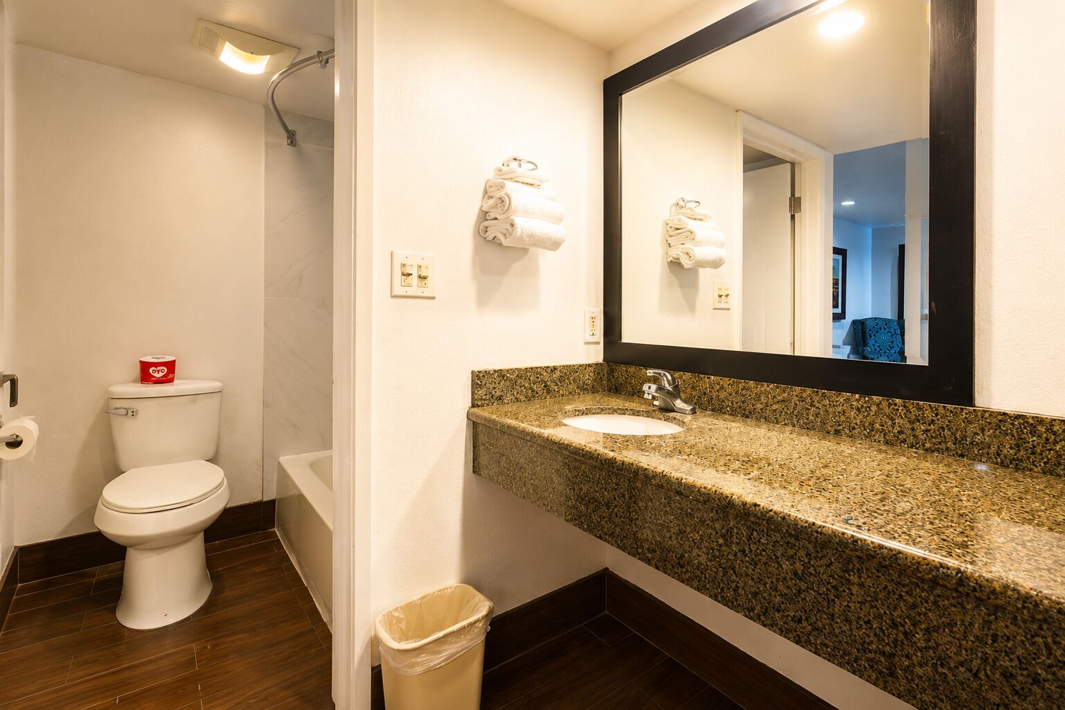Une salle de bain équipée de toilettes, d’un lavabo, d’un miroir et d’une poubelle.