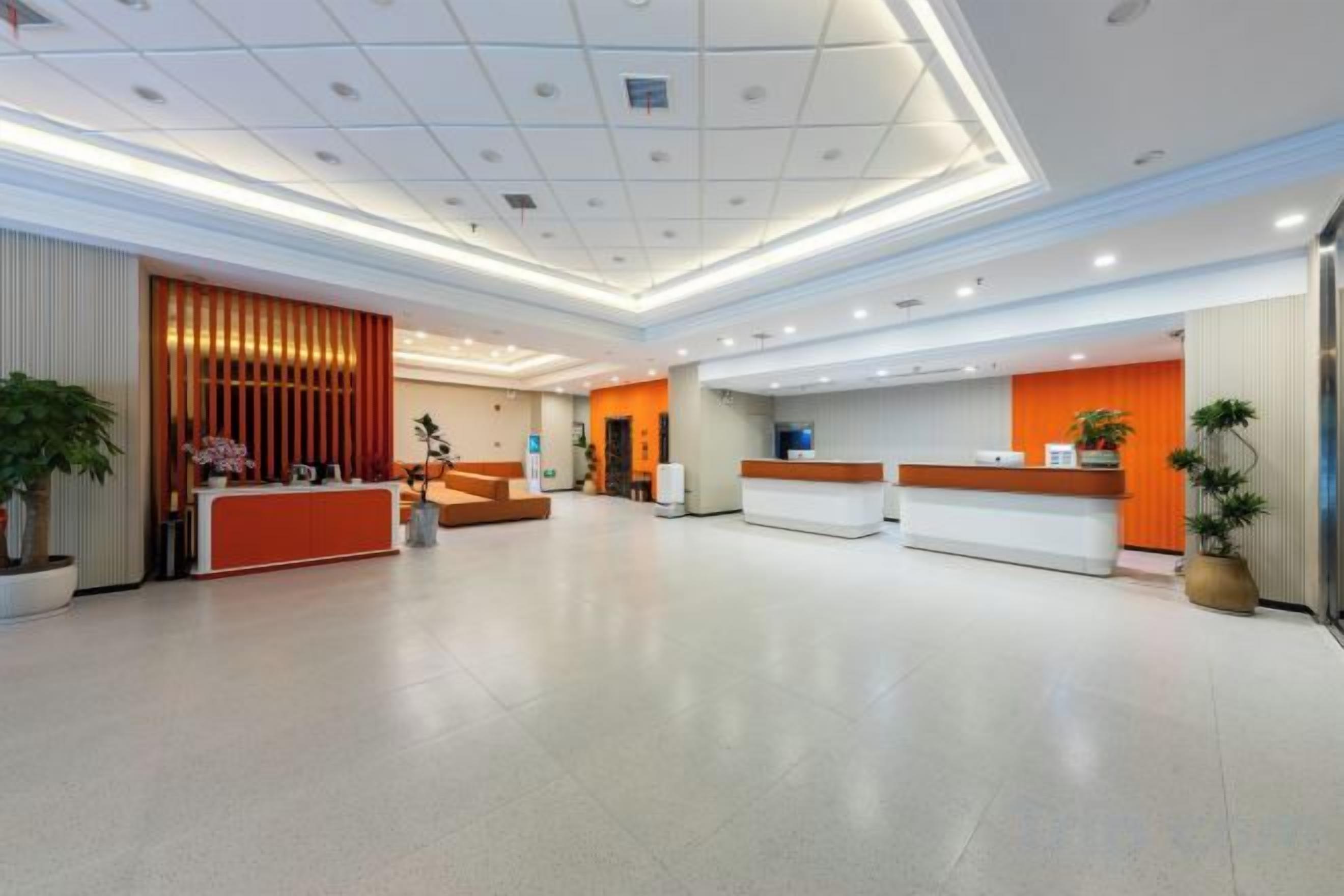 A spacious hotel lobby with a reception desk, seating area, and a large potted plant.