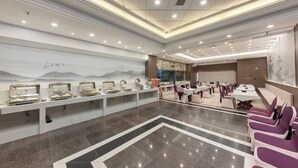 Un hall d’hôtel spacieux, doté d’un long comptoir d’accueil, de plusieurs espaces salon et d’une grande fresque murale.