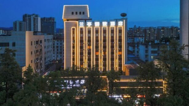 Un hôtel moderne à l’architecture verticale remarquable, doté de nombreux balcons et d’une façade bien éclairée.