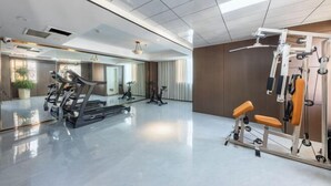 Une salle de sport moderne équipée de tapis de course, de vélos d’appartement et d’appareils de musculation.