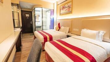 A hotel room with two beds, a desk, and a chair.