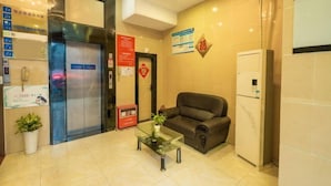 Un área de recepción con una mesa de centro de vidrio, un sofá de cuero, un ascensor y un refrigerador.