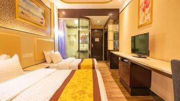 A hotel room with two beds, a TV, a desk, and a glass partition.