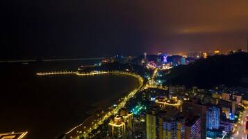 A coastal cityscape at night with illuminated streets and buildings.