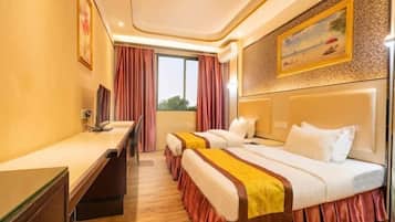 Habitación de hotel con dos camas, un escritorio, una ventana con cortinas y un cuadro en la pared.