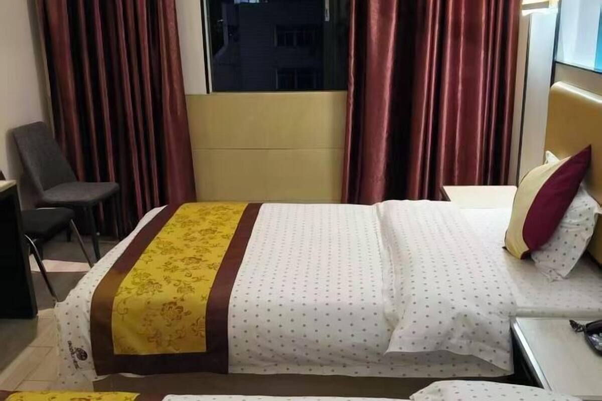 Una habitación de hotel con una cama, una silla, un escritorio y una ventana con cortinas.