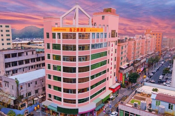 A multi-story building with a prominent sign at the top, surrounded by other buildings and a street. - Daozhilv Hotel (Zhuhai)