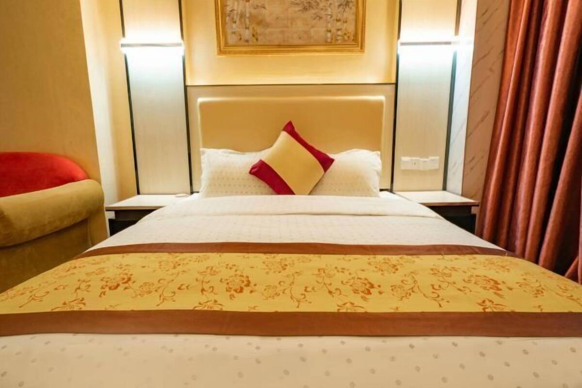 Una habitación de hotel con una cama, una silla roja y un cuadro en la pared.