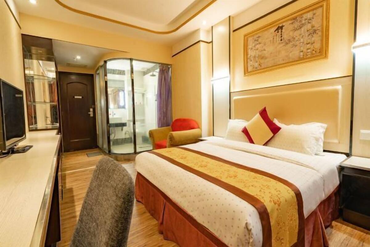 Una habitación de hotel con cama, escritorio, silla y un separador de vidrio.
