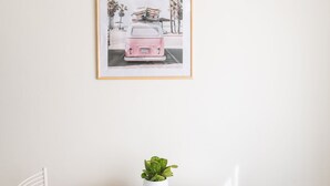 A white table with a framed picture of a pink van and palm trees, a small potted plant, and a menu titled "CAVALIER." - Casa Fubis (Viareggio)