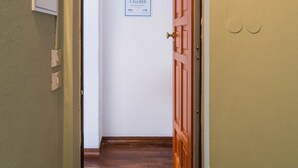 A hallway with a wooden door, a sign on the wall, and a light switch. - Casa Fubis (Viareggio)