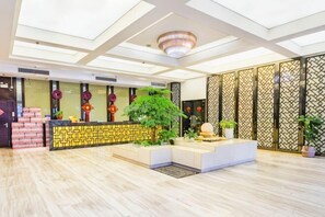 A reception area with a reception desk, potted plants, and a decorative wall. - Focus Hotel (Changsha)