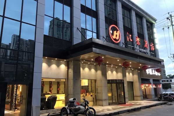 A modern building with a restaurant on the ground floor, large windows, and a motorcycle parked outside.