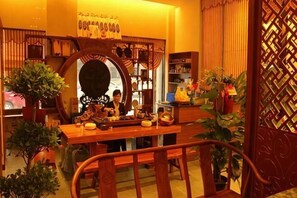 Un interior tradicional con una mesa de madera, sillas y plantas en macetas.