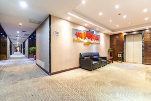 A hotel lobby with a reception desk, seating area, and a large wall with a fruit-themed artwork. - Focus Hotel (Changsha)