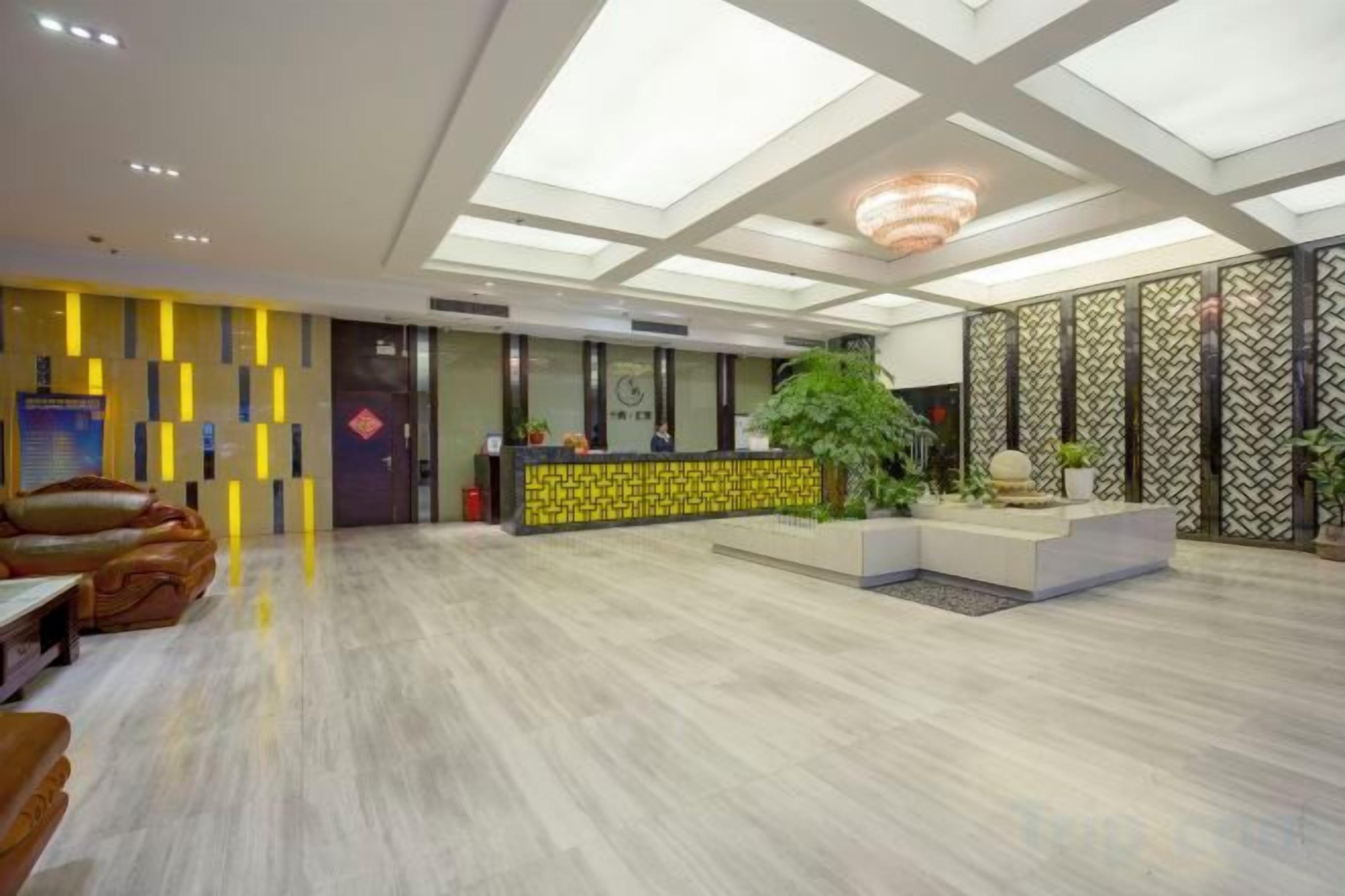 Una hall d'albergo con una reception, un'area salotto e una pianta grande.