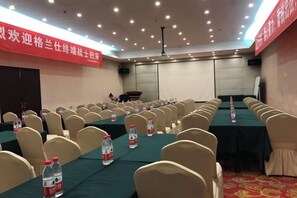 A conference room with rows of chairs, tables, and water bottles. - Focus Hotel (Changsha)