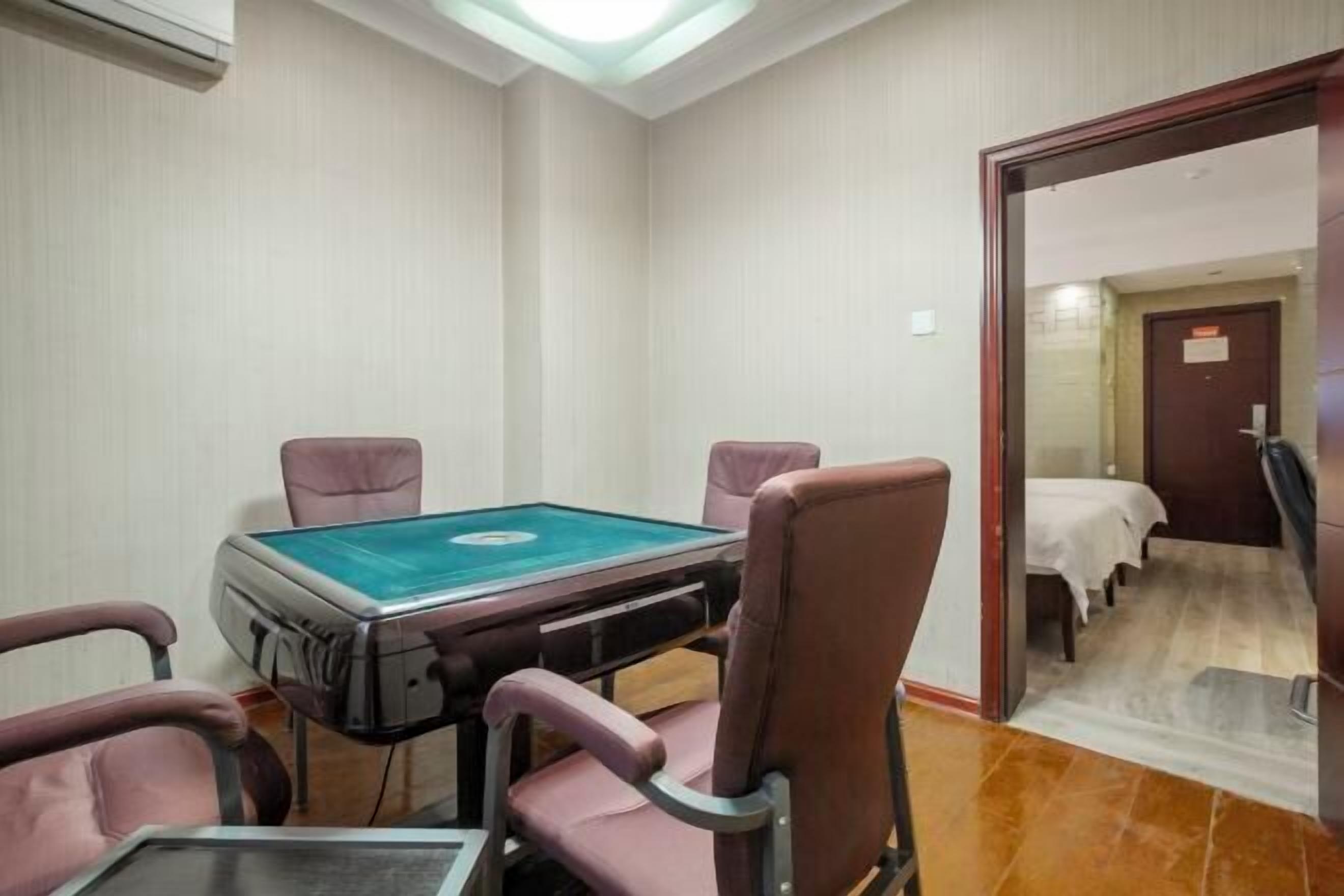 Una habitación con mesa de billar, cuatro sillas, una cama y una puerta que da a otra estancia.
