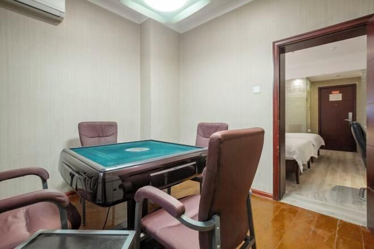 Una habitación con mesa de billar, cuatro sillas, una cama y una puerta que da a otra estancia.