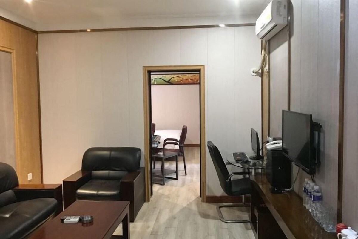 Una habitación de hotel con sofá, escritorio, computadora, televisión y una mesita.