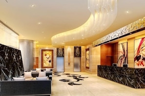 A modern lobby with a curved ceiling, a reception desk, seating area, and artwork on the walls. - Meister Hotel (Chongqing)