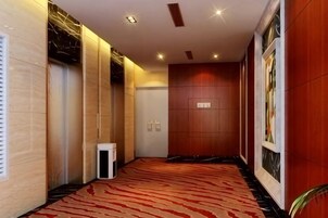 Un pasillo con alfombra roja, una puerta de madera y una pared blanca con una puerta.