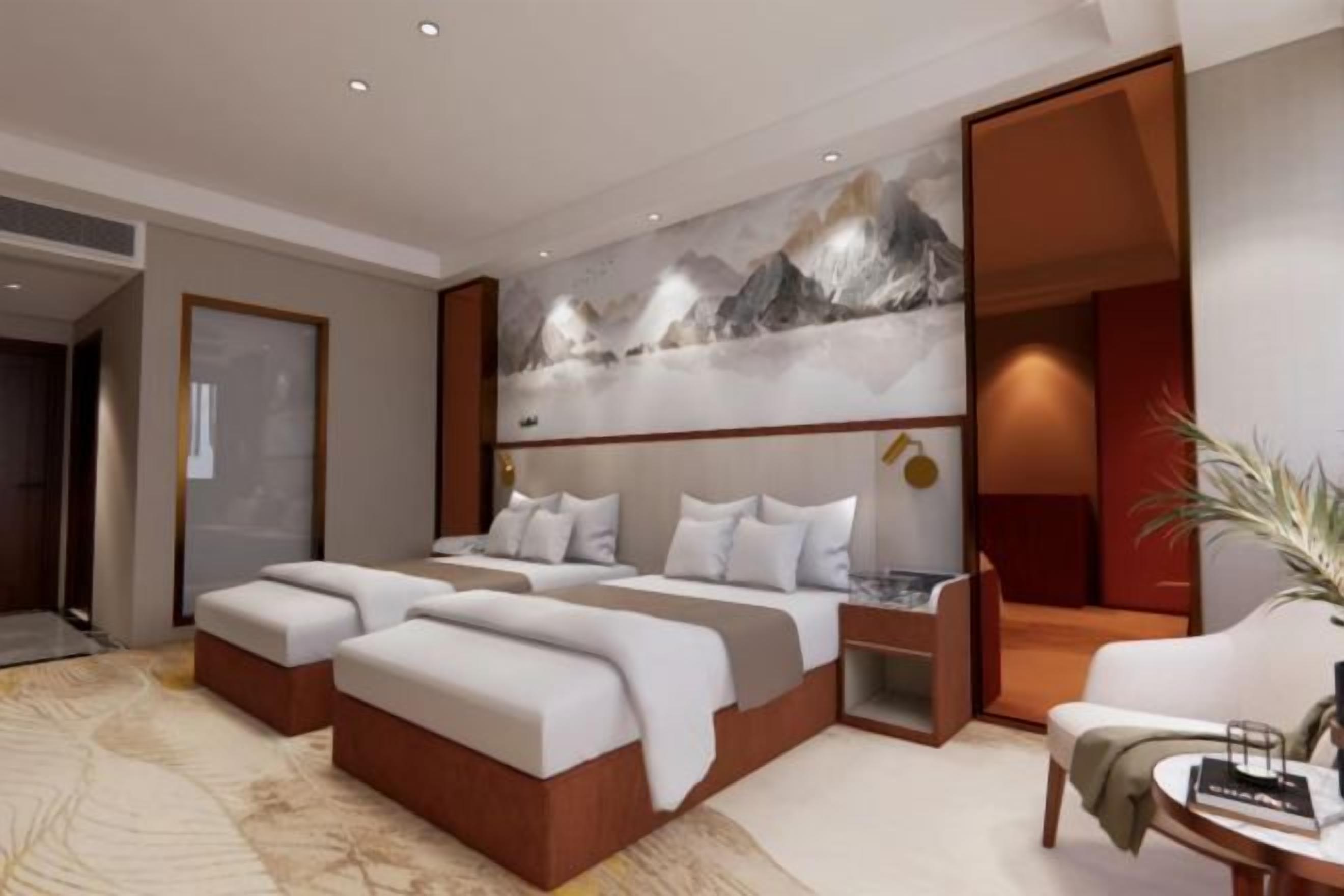 A modern hotel room with a large bed, two bedside tables, a seating area, and a large abstract painting on the wall.