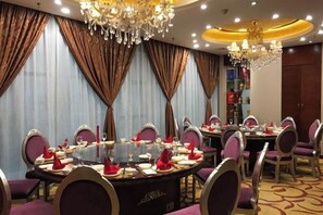 A dining area with round tables, purple chairs, and chandeliers. - Meister Hotel (Chongqing)