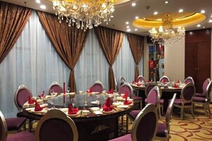 Un comedor con mesas redondas, sillas moradas y candelabros.