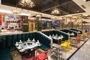 Un restaurante con cabinas y mesas, una barra de servicio de alimentos y lámparas colgantes.