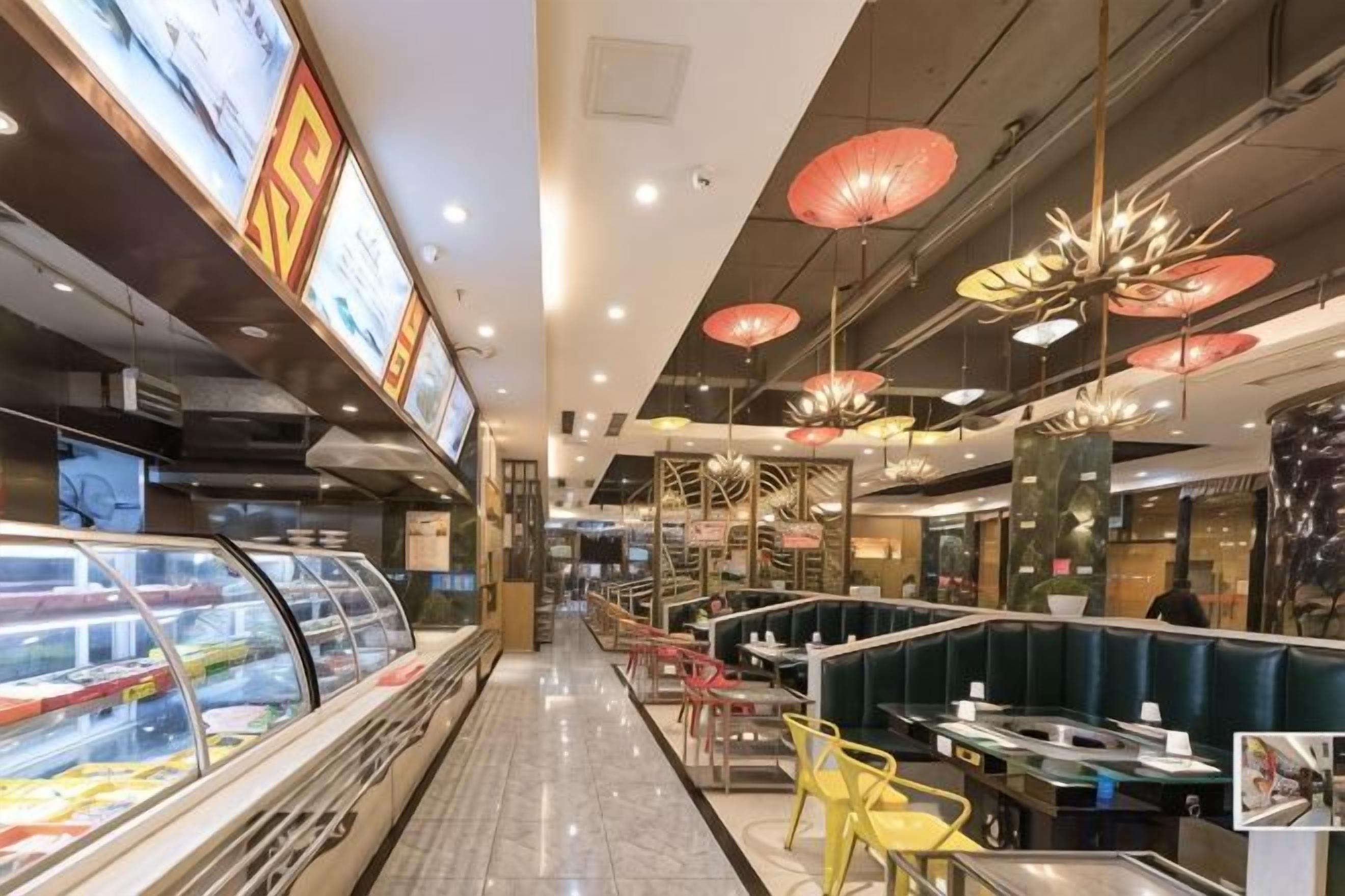 A food court with a glass display case, seating areas, and hanging red umbrellas.