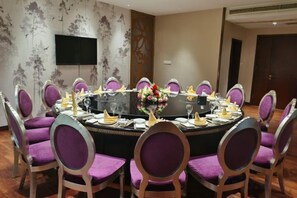 Una sala de conferencias con una mesa redonda, sillas moradas y un centro de mesa floral.