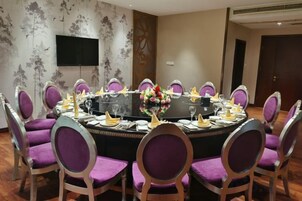 Una sala de conferencias con una mesa redonda, sillas moradas y un centro de mesa floral.
