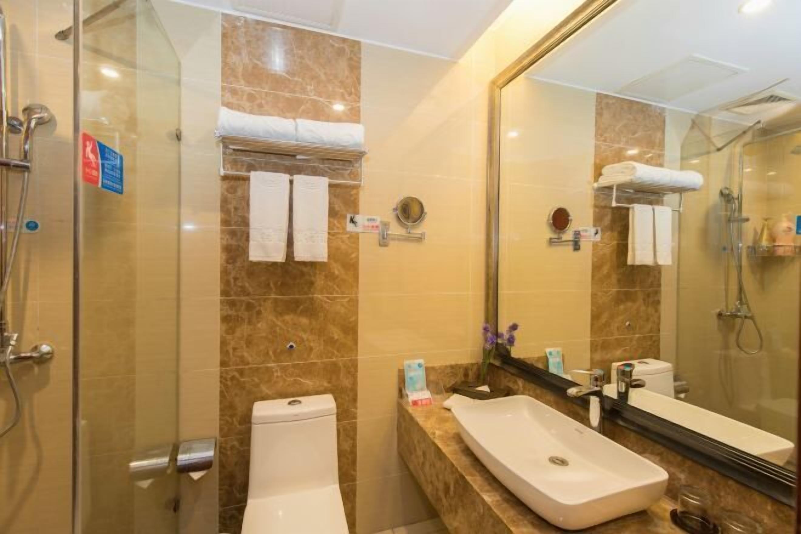 Un bagno con box doccia in vetro, un water bianco, un lavandino con specchio e asciugamani su un portascopevoli.