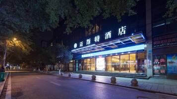 Un hotel con un letrero llamativo, acceso cubierto y fachada bien iluminada.