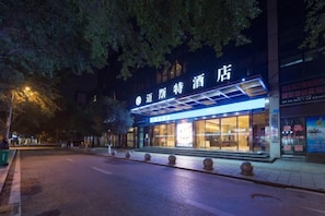 Un hotel con un letrero llamativo, acceso cubierto y fachada bien iluminada.
