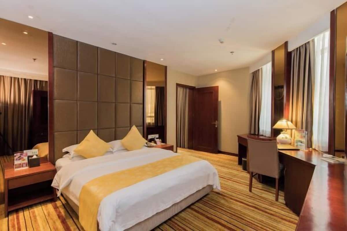 A hotel room with a large bed, a desk, and a chair.