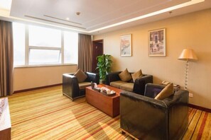 A hotel room with a striped carpet, two sofas, a coffee table, and a plant. - Meister Hotel (Chongqing)