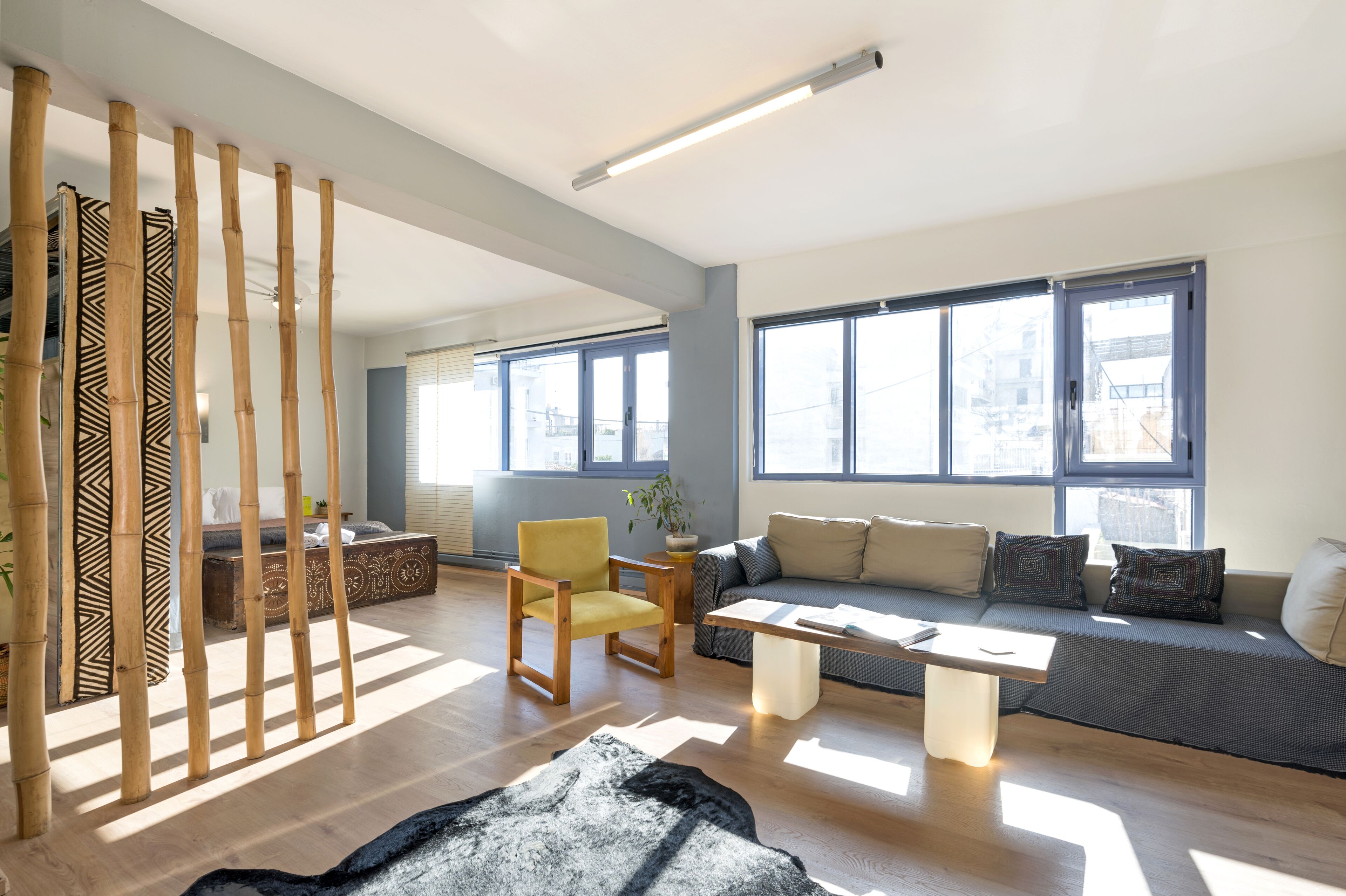 A modern living room with a sofa, a yellow chair, a coffee table, and a decorative bamboo screen.