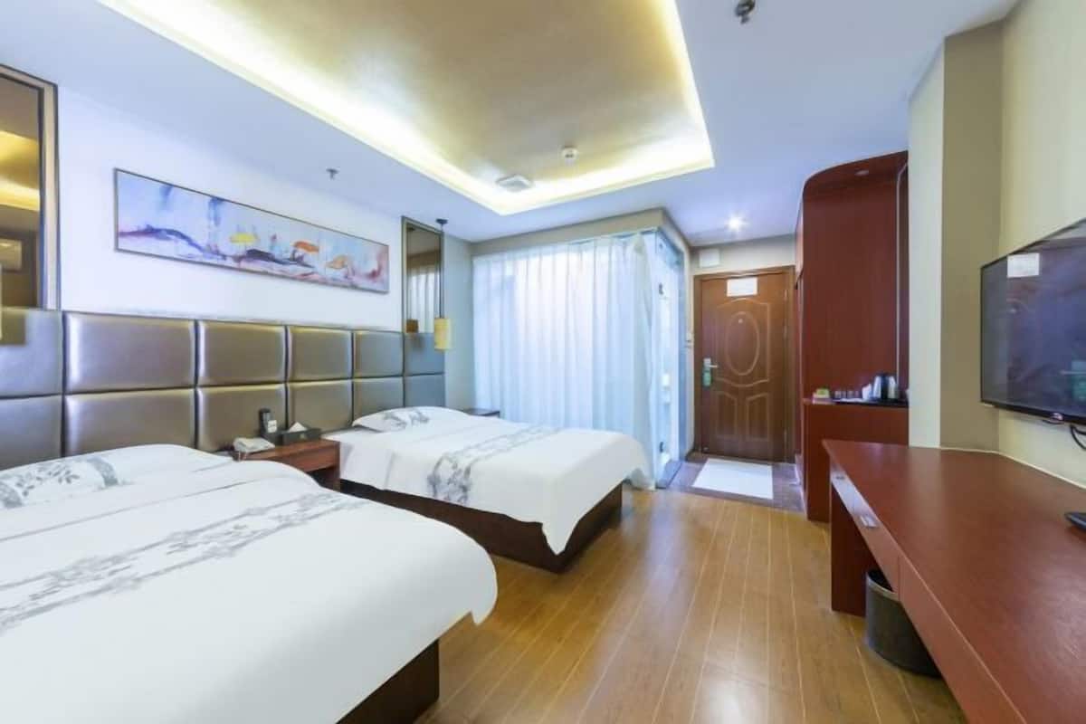 A hotel room with two beds, a flat-screen TV, a desk, and a painting on the wall.