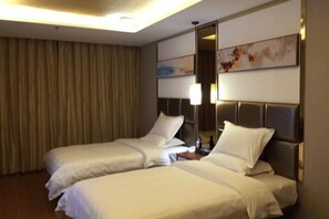 A hotel room with two beds, a nightstand, a lamp, a mirror, and a painting on the wall. - Guanghe Business Hotel (Shaoguan Fengcai Experimental School) (Shaoguan)