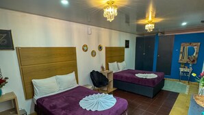 A hotel room with two beds, a chandelier, and a blue accent wall.