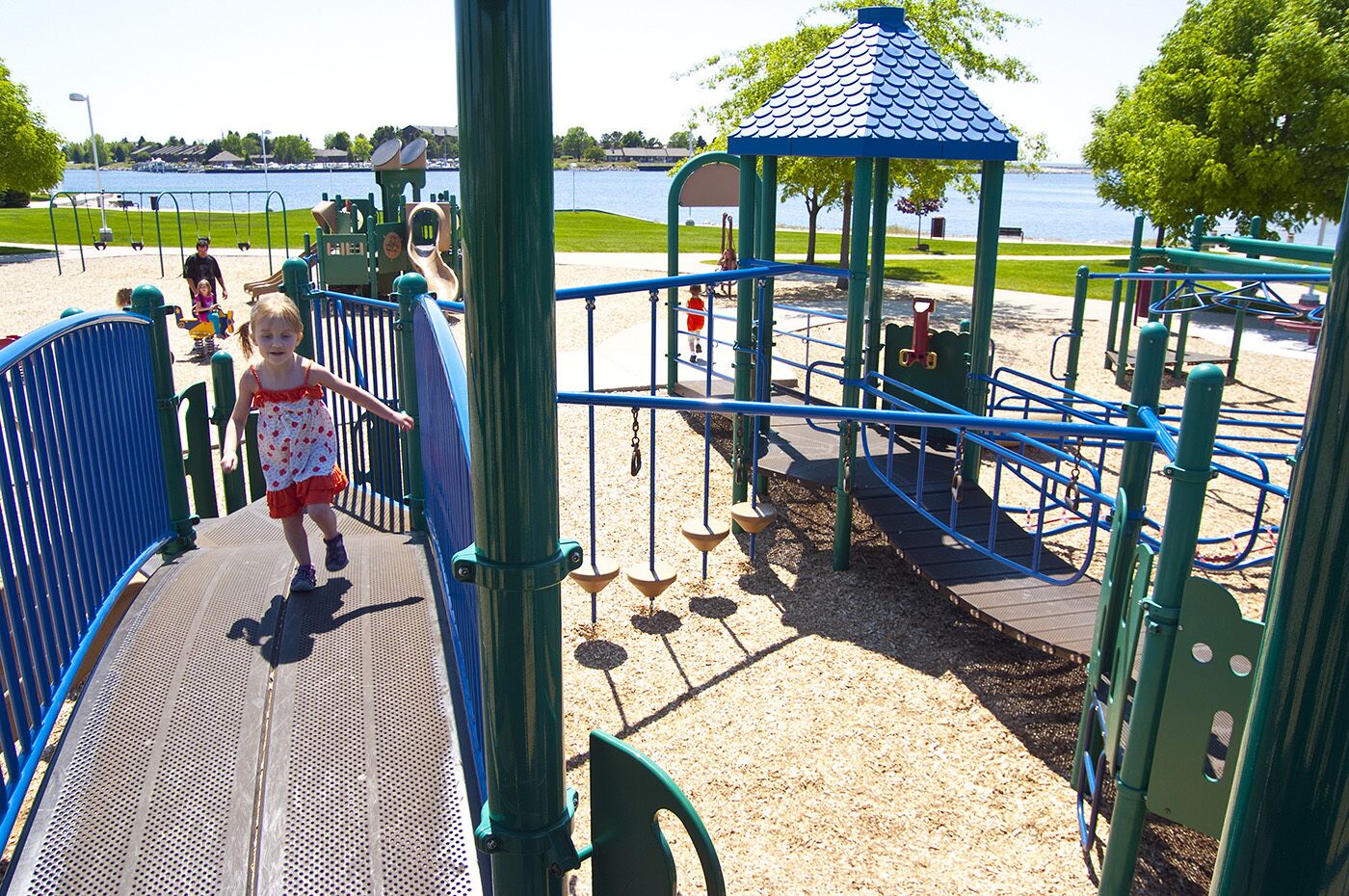 A playground with a slide, climbing structures, and a blue-roofed shelter.