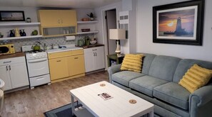 Cozy living space with a kitchenette and seating area, featuring a stove, oven, and microwave, as well as a comfortable sofa and coffee table.