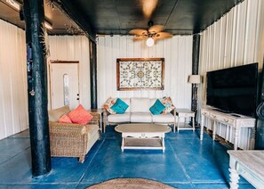 A living room with a sofa, coffee table, television, and decorative items.