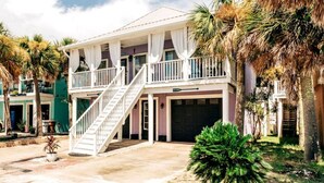 Une maison à deux étages avec un balcon, un garage à l’avant et un escalier menant à l’entrée.