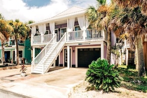 A two-story house with a balcony, a front garage, and a staircase leading to the entrance.