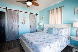 A bedroom with a bed, curtains, a ceiling fan, and a starfish decoration.